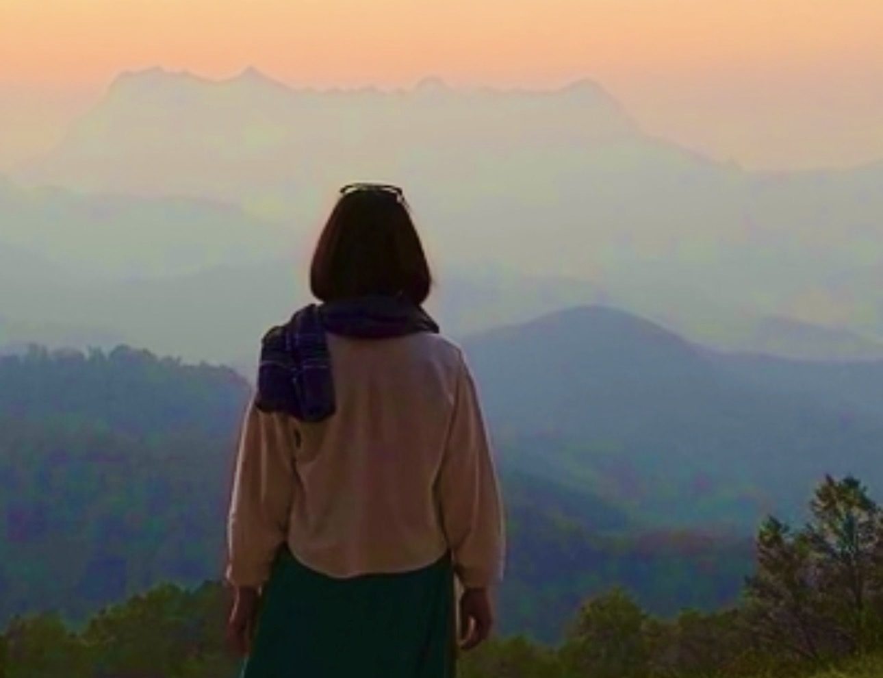 日の出前の山を見つめる女性の後ろ姿